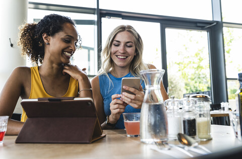 Best friends meeting in cafe, talking and sharing news, using digital tablet stock photo