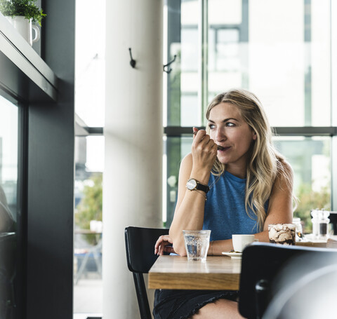 Young woman in cafe, drinking coffee and eating sweets stock photo