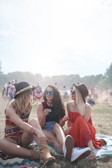 Junge Leute sitzen auf einer Decke bei einem Musikfestival - ABIF00594