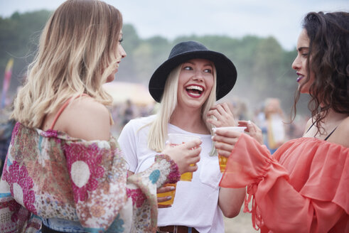 Freunde trinken Saft und sitzen auf einer Wiese während eines Musikfestivals - ABIF00612