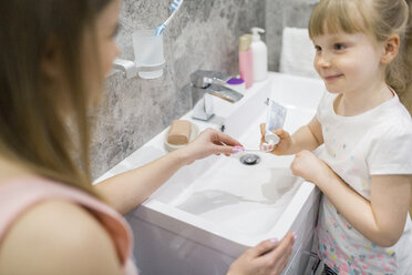 Mother and daughter brushing teeth in bathroom - AWF00067