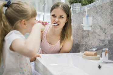 Mother and daughter brushing teeth in bathroom - AWF00068