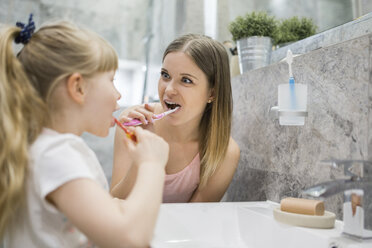 Mother and daughter brushing teeth in bathroom - AWF00069