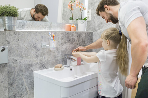 Fahtehr hilft seiner kleinen Tochter beim Händewaschen, lizenzfreies Stockfoto