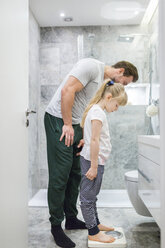 Vater und Tochter überprüfen ihr Gewicht auf der Badezimmerwaage - AWF00089