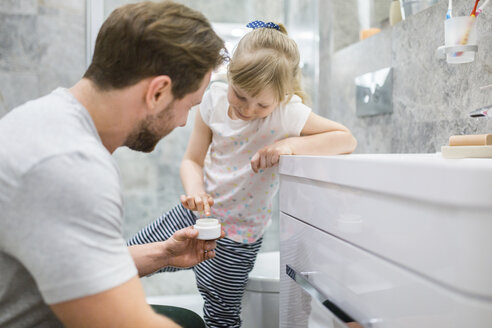 Vater und Tochter verwenden Gesichtscreme im Badezimmer - AWF00091