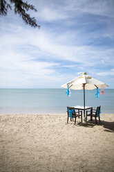 Thailand, Khao Lak, Tisch, Stühle und Sonnenschirm am Meer - CHPF00476