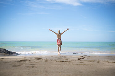 Thailand, Khao Lak, back view of happy woman standing on the beach at seaside - CHPF00480
