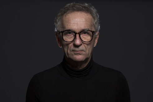 Portrait of serious senior man wearing glasses in front of dark background - AWF00094