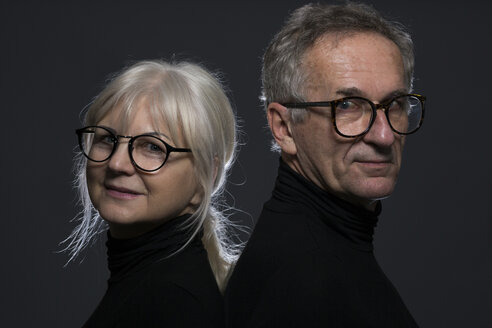 Portrait of senior couple wearing glasses in front of dark background - AWF00096