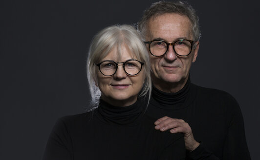 Portrait of senior couple wearing glasses in front of dark background - AWF00097