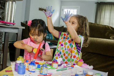 Two young girls sitting at table, making art, using paint - ISF12679