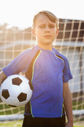 Porträt eines Jungen, der einen Fußball vor einem Tor hält - ISF12683