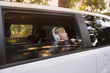Junge mit Kopfhörern, der aus dem Autofenster starrt - ISF12690