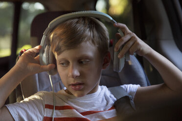 Junge auf dem Rücksitz eines Autos entfernt Kopfhörer - ISF12699