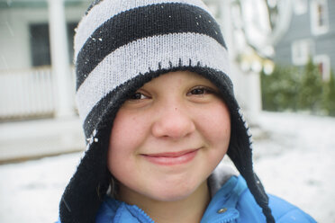 Nahaufnahme eines Mädchens mit schwarz-weiß gestreiftem Hut in einem verschneiten Garten - ISF12702