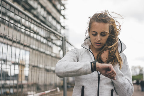 Sportliche junge Frau im Freien mit Blick auf die Uhr - KNSF03990