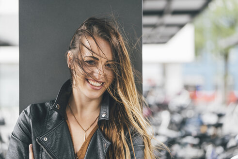 Porträt einer glücklichen jungen Frau mit vom Wind zerzaustem Haar - KNSF03993