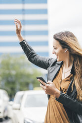 Happy young woman with in-ear phones and cell phone - KNSF03995