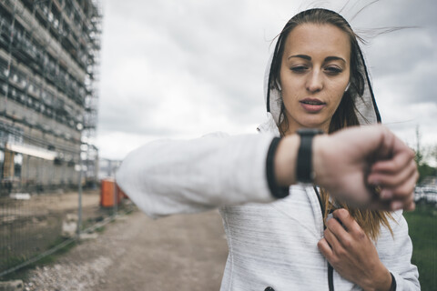 Sportliche junge Frau im Freien mit Blick auf die Uhr, lizenzfreies Stockfoto