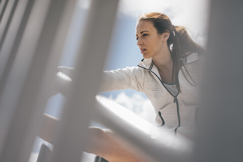 Sportliche junge Frau streckt sich am Geländer, lizenzfreies Stockfoto