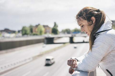 Sportliche junge Frau mit Blick auf die Uhr auf der Autobahn, lizenzfreies Stockfoto