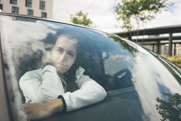 Sportive young woman in car looking out of window - KNSF04038