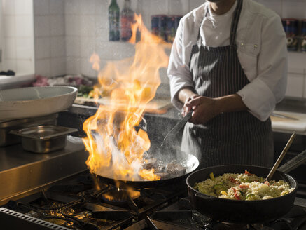 Koch beim Kochen in der Küche mit brennender Pfanne - CVF00846