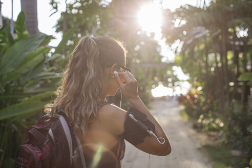 Thailand, Koh Phangan, Sportliche Frau mit Kopfhörern, die sich auf ihr Training vorbereitet - MOMF00456