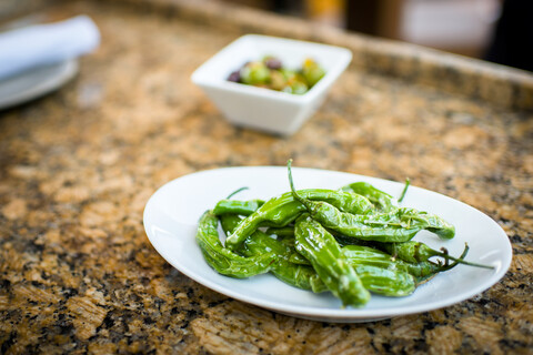 Teller mit grüner Chilivorspeise auf dem Restauranttisch, lizenzfreies Stockfoto