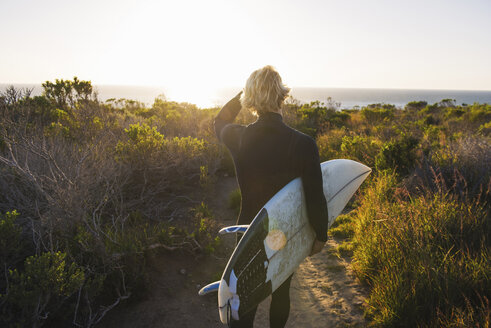 Rückansicht eines jungen männlichen Surfers mit Surfbrett bei Sonnenaufgang - ISF12782