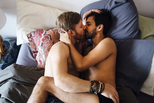 Männliches Paar, teilweise bekleidet, auf dem Bett liegend, küssend - ISF12843