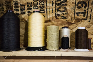 Row of thread bobbins on workshop shelf - ISF12920