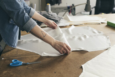 Young female seamstress folding pattern component in fashion studio - ISF12958