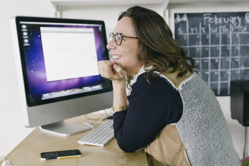 Portrait of young female office worker daydreaming at desk - ISF12965