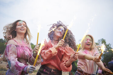 Freunde mit Wunderkerzen tanzen auf einem Musikfestival - ABIF00634