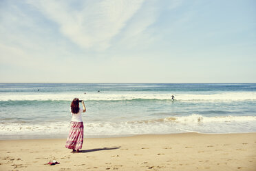 Rückansicht einer Frau am Strand beim Fotografieren des Ozeans, Venice Beach, Los Angeles, Kalifornien - ISF13004