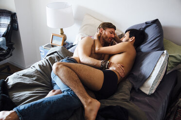 Male couple, partially dressed, lying on bed, embracing - ISF13041