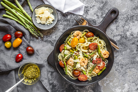 spaghetti with shrimps, green asparagus, tomato, pesto and parmesan stock photo