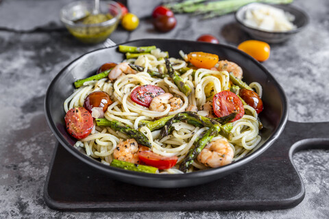 spaghetti with shrimps, green asparagus, tomato, pesto and parmesan stock photo