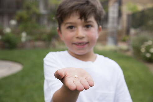 Porträt eines Jungen, der einen Zahn in der Hand hält, Fokus auf die Hand - ISF13075