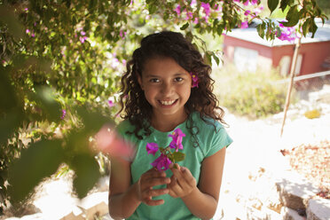 Portrait of girl in garden holding pink blossom - ISF13173