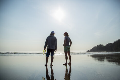 Silhouettenansicht von zwei jungen Männern, die sich am Short Sands Beach, Oregon, USA, unterhalten - ISF13184