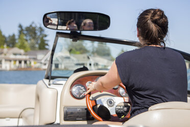 Rückansicht einer jungen Frau, die ein Motorboot fährt, Lake Oswego, Oregon, USA - ISF13199