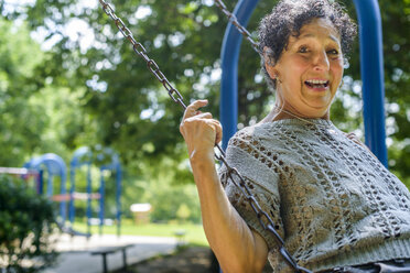 Porträt einer älteren Frau beim Spielen auf einer Parkschaukel - ISF13201