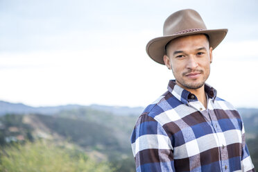 Portrait of young man wearing cowboy hat on rural hill - ISF13208