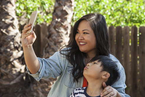 Mutter und Sohn posieren für ein Smartphone-Selfie im Garten - ISF13245