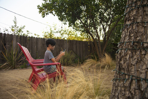 Junge spielt ein Spiel auf einem digitalen Tablet im Garten - ISF13257