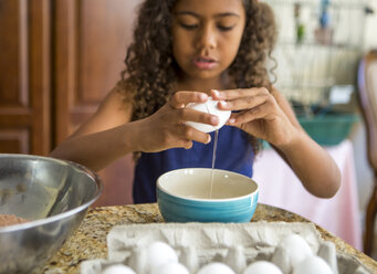 Girl cracking eggs into bowl looking down - ISF13262