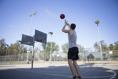 Junger männlicher Basketballspieler, der den Ball in Richtung des Basketballkorbs wirft - ISF13289